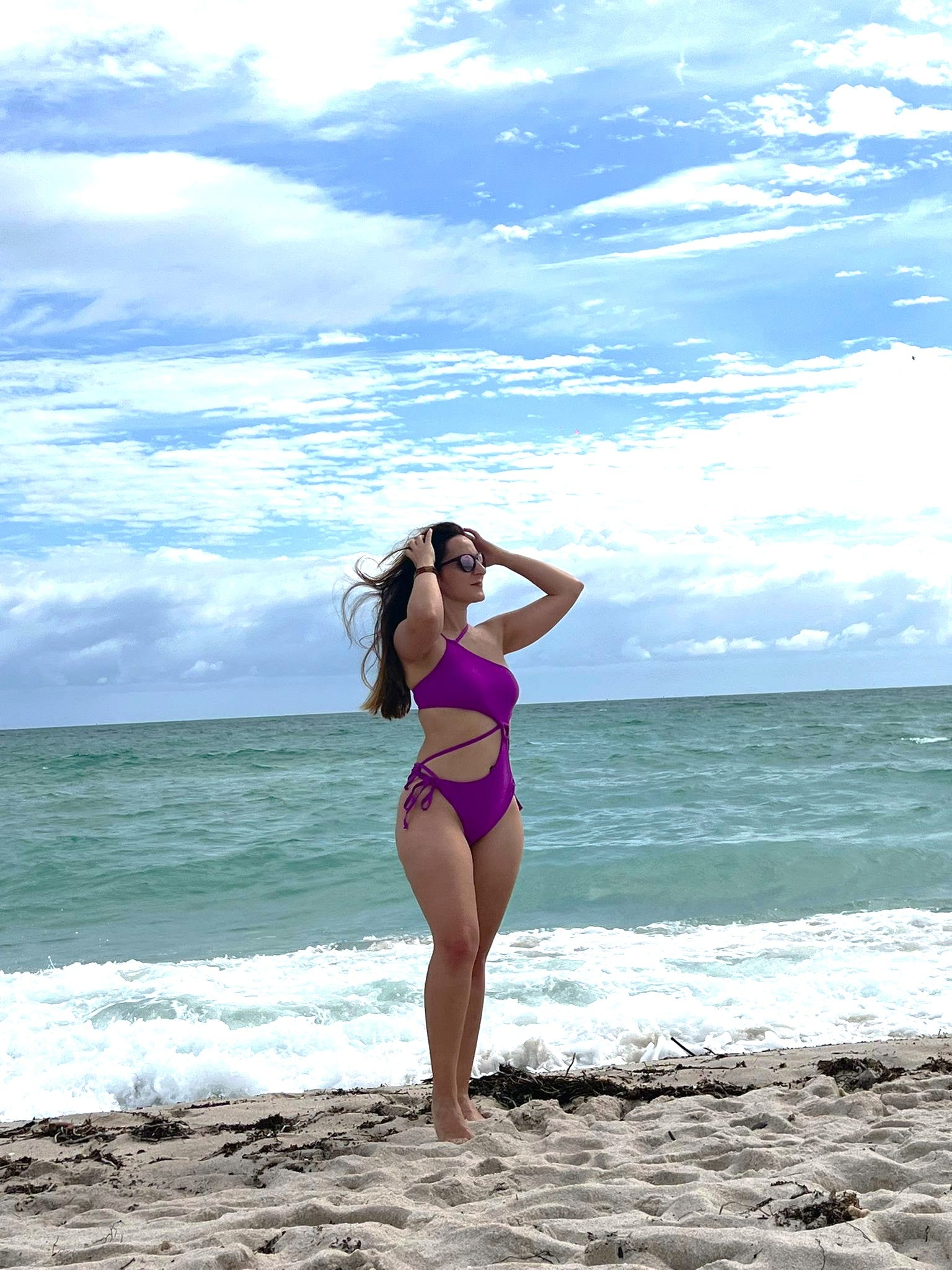 ESAMY The Sway Asymmetrical One-Piece Swimsuit in Unicorn - Pink Beach Lifestyle Side View with One-Shoulder Design, Cut-Out and Dig-Free Side Ties